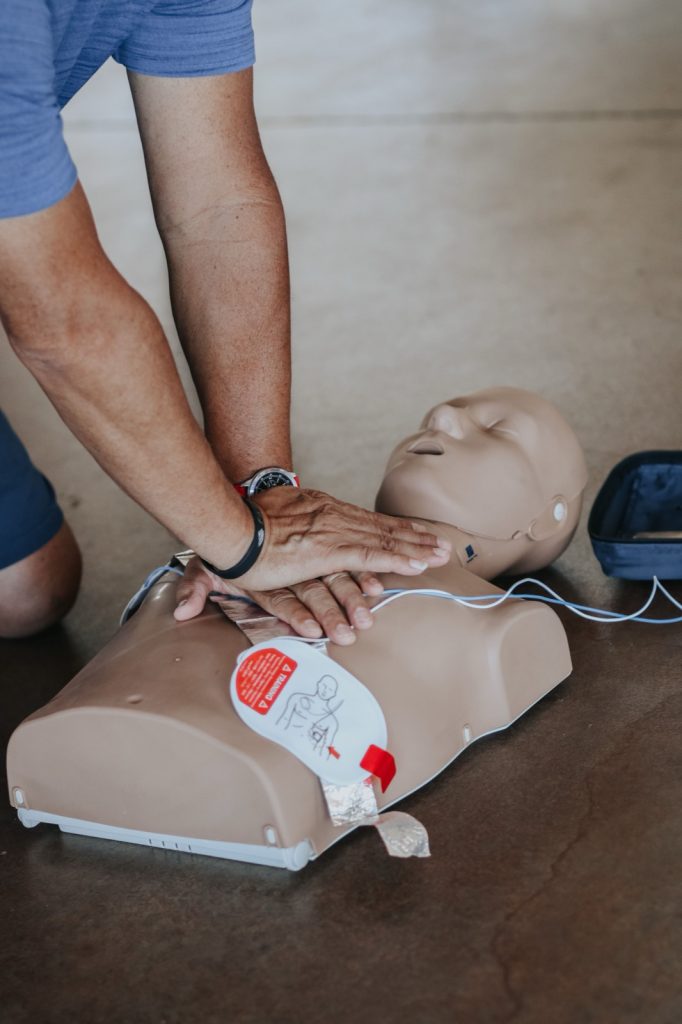 Participant practicing CPR on a training manikin with AED pads