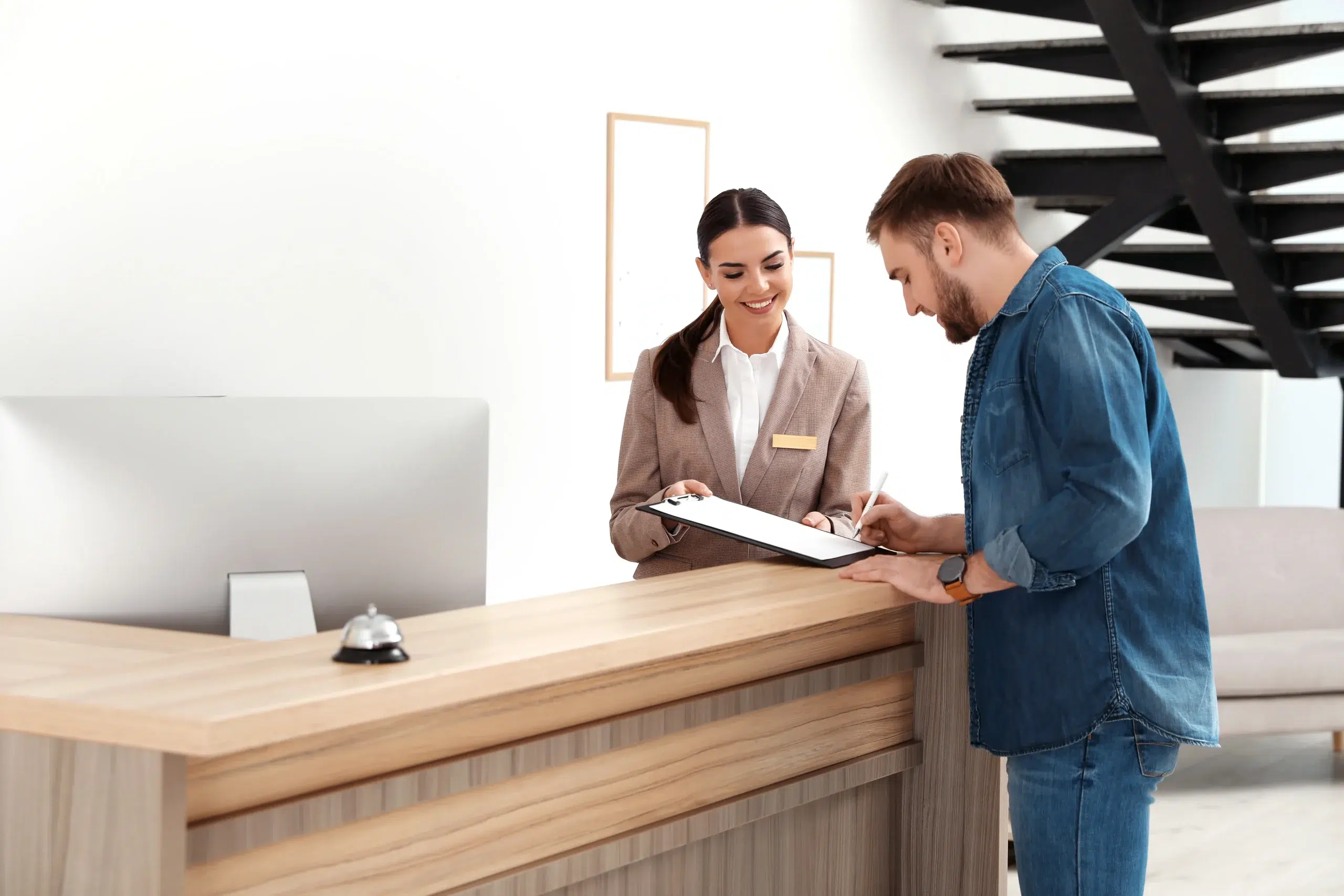 Hotel front desk employee assisting a guest with check-in.