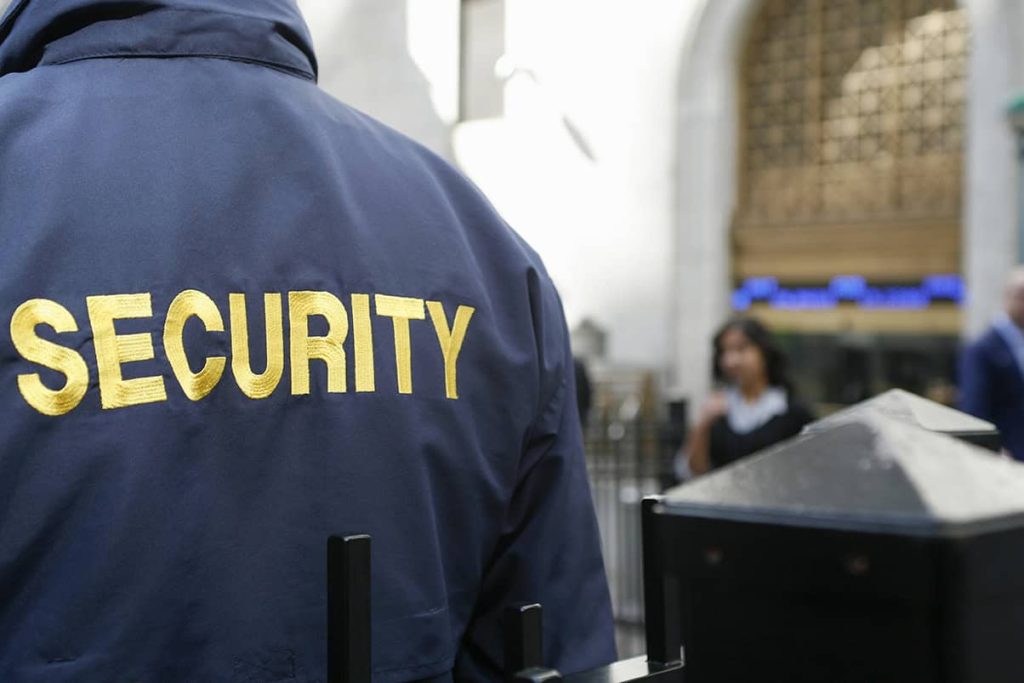Uniformed security officer at an entrance, with SECURITY lettering on the back